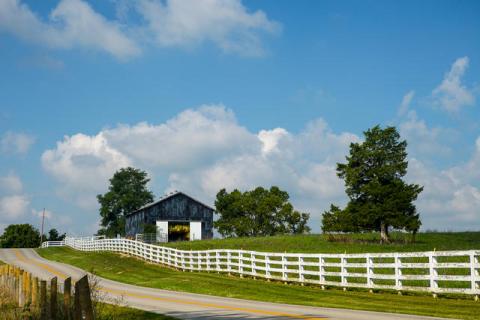 white fence through field with barn